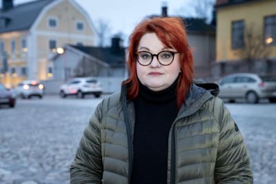 En kvinna med rött hår och grön vinterjacka står utomhus i Gamla stan i Borgå.