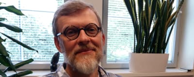 Johannes Brusila, en man med rutig skjorta, skägg och runda glasögon.