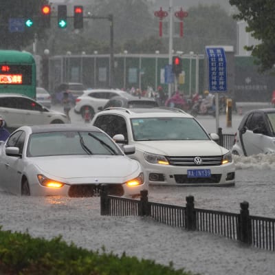 Bilar åker på översvämmad väg i Zhengzhou i Kina.