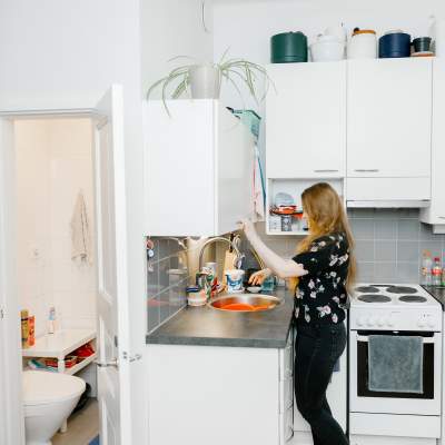 En kvinna står och diskar i ett kök.