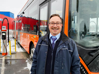 Frank Ahrenberg framför en orange elbuss.