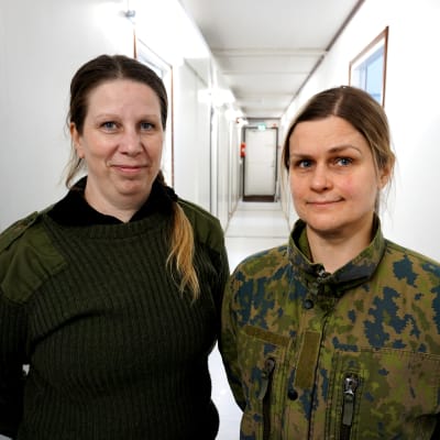 Två kvinnor i militäruniform står i en korridor.