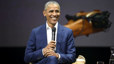 Barack Obama ler stort med en mikrofon i händerna.