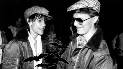 Iggy Pop och David Bowie småleende på sjuttiotalet med kepsar på huvudet.