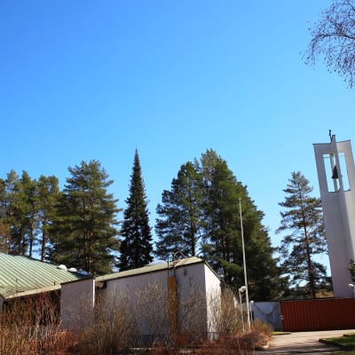 Kuvassa näkyy valkoseinäinen ja vihreäkattoinen Lohikosken seurakuntakeskus sekä avoin ja pelkistetty kellotorni.