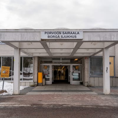 Ingång till vit, låg byggnad som det står "Borgå sjukhus" på. 