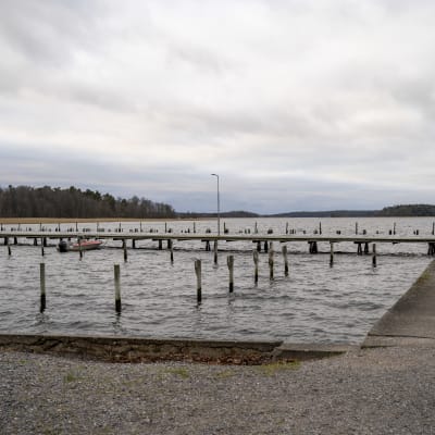 bryggor och pålar på vatten. En ensam båt förtöjd vid en brygga. Barckens udde, Ekenäs. Höst, november 2021