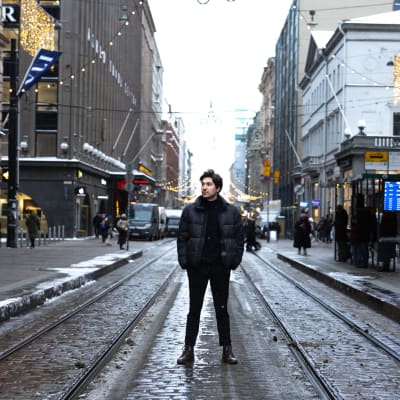 En ung man står mitt på Alexandersgatan i centrala Helsingfors.