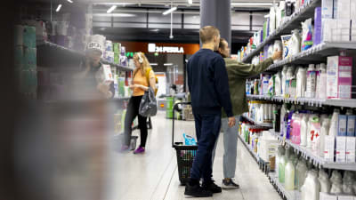 En ung man och en kvinna står vid en butikshylla.
