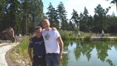 Två män står framför en liten damm.