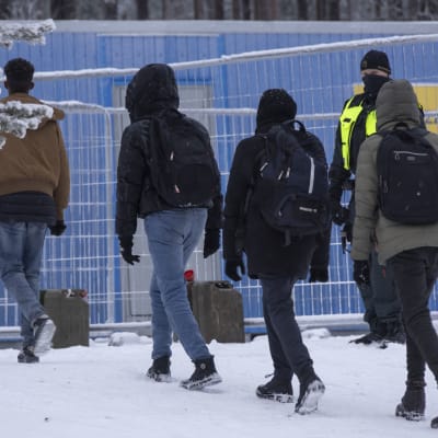 Mahdollisia turvapaikanhakijoita kävelemässä jonossa.