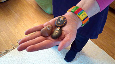 Isela håller i sin hand tre målade stenar - en amdonna, en nunna och en präst.