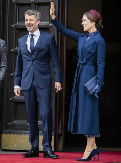 Kronprins Frederik skrattar och kronprinsessan Mary vinkar. Båda är klädda i blått.