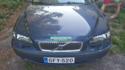 Uudehko sininen Volvo edestäpäin kuvattuna. Auton konepellissä on vihgreä tarra, jossa lukee" biokaasuauto".