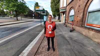 Regina Laurén från Röda korset står iklädd insamlingsväst utanför kontoret i Helsingfors.