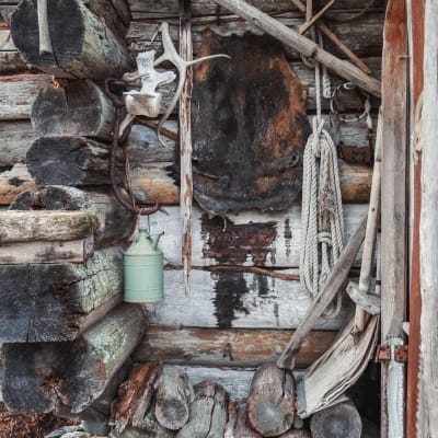 Skinnfäll, djurhorn och verktyg hänger på en vägg av torrfura.