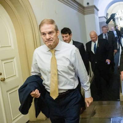 Jim Jordan bär sin kavaj på armen och ser sammanbiten ut. 
