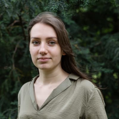 Julia Ståhle står vid en buske och tittar in i kameran.