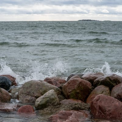 Vågor slår mot en strand med stenar.