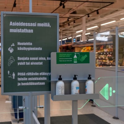 Ohjeistusta sekä käsidesipulloja S-marketin sisäänkäynnillä.