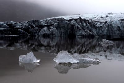 Solheimajökullin jäätikkö Islannissa. Etualalla jäätikön palasia kellumassa vedessä. 23.10.2021