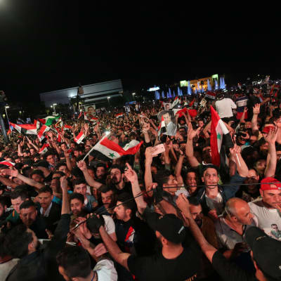 Hundratals människor firar och viftar med syriska flaggor.