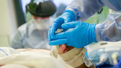 Närbild på en hälsovårdare som håller i handen på en patient. 