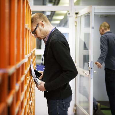 Työntekijä nojaa otsallansa työpaikan postilokerikkoihin.