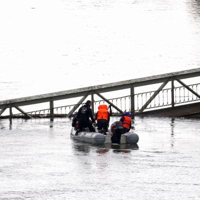 Pelastustyöntekijät kumiveneessä joessa olevan sillan luona.