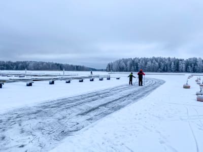 Två personer åker bortåt från kameran på en isväg över isen.