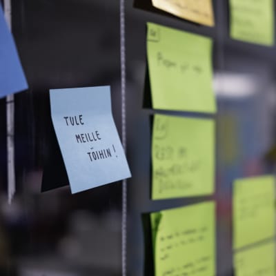 "Tule meille töihin" post-it lappu seinällä.
