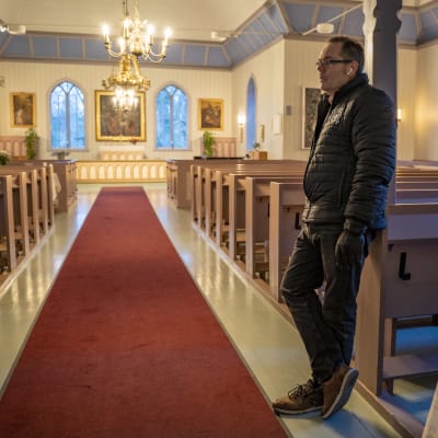 Man står i kyrkogång vid en röd matta.