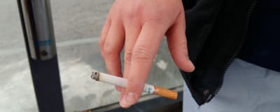 En hand som håller i en cigarett mellan pek- och långfingret.