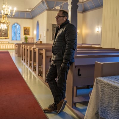 Man står i kyrkogång vid en röd matta.