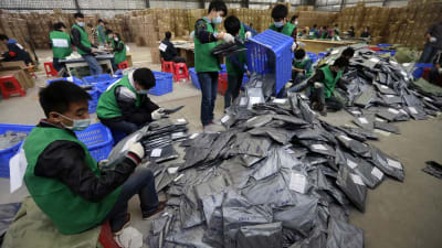 Kinesiska anställda vid logistikcentral sorterar nätförsändelser.