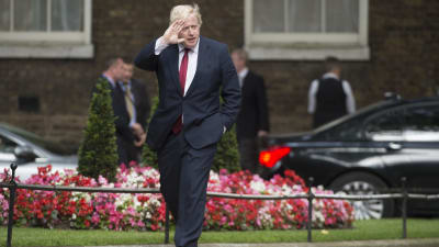 Boris Johnson i svart kostym och röd slips på väg till 10 Downing Street.