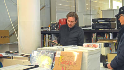 Mikael Winogradow visar vinylskivor som han håller i åt en kund.