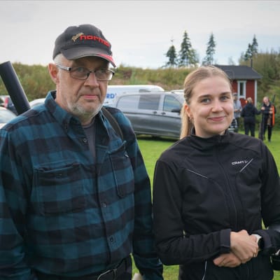 En man i rutig skjorta och en kvinna i svart jacka ler mot kameran.