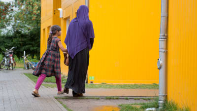 En mamma och sin dotter i ett bostadsområde.