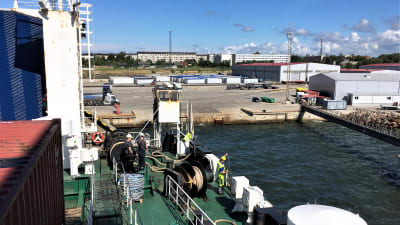 Ett fartyg anlöper hamn i Paldiski i Tallin. Sommar, blå himmel. Fotograferat från båten mot hamnen. Ganska tomt på folk, bilar och annat i hamnen.