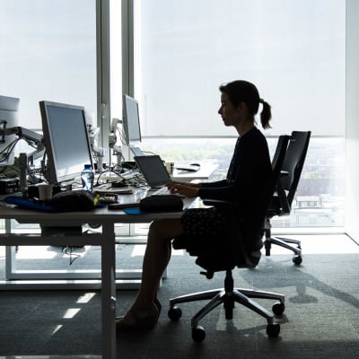 Nainen istuu tietokoneella toimistossa.