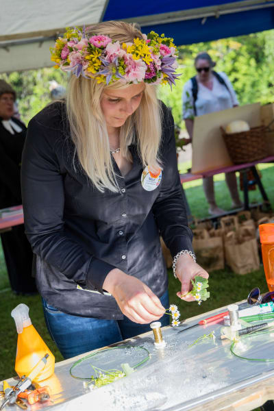Floristmästaren Nelly Koitto med en blomstarkrans i sitt hår arbetar med små snittblommor.