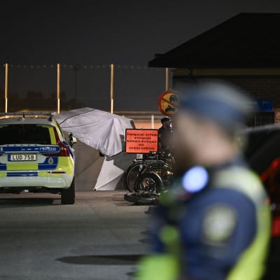 Svensk polis vid polisbilar, bilden tagen vid sportplan där en ung man sköts ihjäl. 