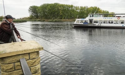 Paikalliset kalastajat kalastamassa, kun jokilautta saapuu Khersonin asukkaiden kanssa evakuoituna Khersonista Ukrainan Khersonin alueen Oleshky-penkereelle 25.10.2022.