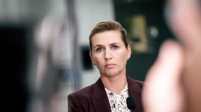 Danmarks statsminister Mette Frederiksen ser allvarlig ut i mörk kavaj och småblommig blus.