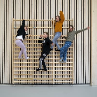 Fyra skolelever i trapetser i en nybyggs gymnastiksal.