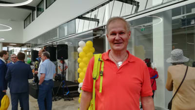 Besökare Marko Ranne var glad över att köpcentrumet äntligen har öppnat. Han står inne i köpcentrumet med ballonger i bakgrunden.