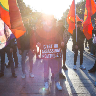 En demonstration i Toulouse, Frankrike, där en person står med en skylt där det står "C'est un assassinat politique!"