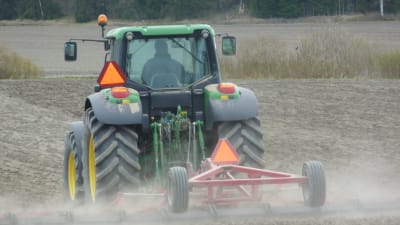 En traktor med harv på en åker.