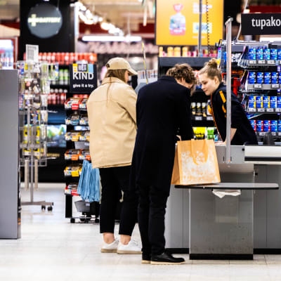Ruokakaupan kassahenkilö asiakkaan kanssa.